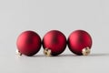 Three red matte Christmas balls on a seamless grey background