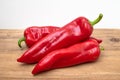 Three red peppers lie on a wooden table Royalty Free Stock Photo