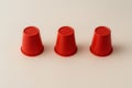 Three red plastic cups arranged in a simple line on a neutral background. Shell game, party, or minimalist design element Royalty Free Stock Photo