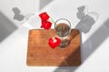 Three red poppies flowers in glass vase with water on white table and wooden background with contrast sun light and shadows close