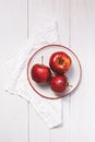 Three red ripe apples on a plate. Top view on a wooden table Royalty Free Stock Photo