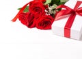 Three red roses, gift with red ribbon on the white wooden background. Women`s day, mother day, valentines day, happy birthday