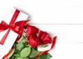 Three red roses, gift with red ribbon on the white wooden background. Women`s day, mother day, valentines day, happy birthday
