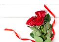 Three red roses with red ribbon on the white wooden background. Women`s day, mother day, valentines day, happy birthday