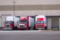 Three red semi trucks are among the dock for loading trailers Royalty Free Stock Photo