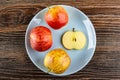 Three red striped apples, slice of apple in plate on wooden table. Top view Royalty Free Stock Photo