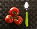 Three red tomatoes branch with green spoon