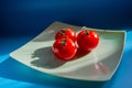Three red tomatoes lie on a plate in the sunlight Royalty Free Stock Photo