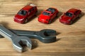 Three red toy cars and toy spanners on a wooden background