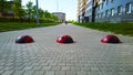 Three red traffic barrier on pedestrian path as concrete hemispheres like red ladybird near residential building. Speed bump. Slee