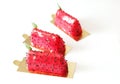 Three red watermelon glazed desserts with black sesame seeds and basil leaves on golden coasters