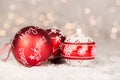 Three red and white christmas balls laying in snow with soft bokeh of white christmaslights Royalty Free Stock Photo