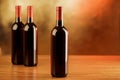 Three red wine bottles on wooden table and golden background Royalty Free Stock Photo