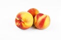 Three red and yellow coloured peaches on white ground