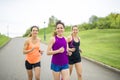 Three relaxed woman runners on a paved jogging daylight