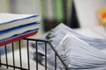 Three of report notebook on black shelf rack and pile of white data papers sheet