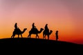 Three Riders And Their Handler Travel Through The Saharan Desert On Their Camels In Morocco Royalty Free Stock Photo