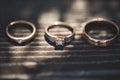 Three rings on wooden background. Engagement ring and two wedding bands on wooden table. White gold wedding jewelry. Royalty Free Stock Photo