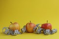 Three ripe apples and tape measure on a yellow background. Weight loss concept Royalty Free Stock Photo