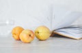Three ripe apricots on background of open pages of book Royalty Free Stock Photo