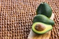 Three ripe avocados on wooden background: two whole and one cut. Royalty Free Stock Photo