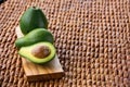 Three ripe avocados on wooden background: two whole and one cut. Royalty Free Stock Photo