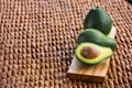 Three ripe avocados on wooden background: two whole and one cut. Royalty Free Stock Photo