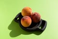 Three ripe juicy fluffy peach or nectarine on wooden serving plate. Bright sunlight & shadow, copy space Royalty Free Stock Photo