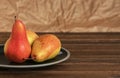 Three ripe pears in a ceramic plate on a wooden background. Organic fruits close up. Space for text. Fresh seasonal produce. Royalty Free Stock Photo