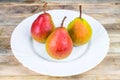 Three ripe pears in white plate on rustic wooden table Royalty Free Stock Photo