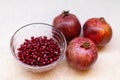 Three ripe pomegranates, a bowl of red seeds on a light table, close-up. Healthy lifestyle concept, veganism, vegetarianism, food Royalty Free Stock Photo