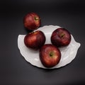 Three ripe red apples lie on a white plate in the form of a leaf. Royalty Free Stock Photo