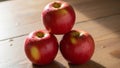 Three ripe red apples are stacked in a triangular formation on a wooden Royalty Free Stock Photo