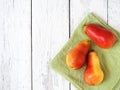 Three ripe red pears against a white wooden background. Top view. Green napkin. Free space for text