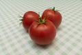 Three ripe red tomatoes on a light checkered tablecloth Royalty Free Stock Photo