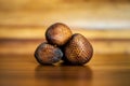 Three ripe whole salak or shake fruits lying on wooden background. Exotic fruits from Bali, Indonesia