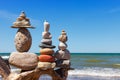 Three Rock Zen pyramid of balanced stones on a background of the summer sea and blue sky