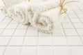 Three rolled clean white cotton terry textile bath towels on white tile background Royalty Free Stock Photo