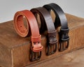 Three rolled leather belts of different colors displayed on wooden podium steps Royalty Free Stock Photo