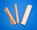 Three rolled rolls with brown parchment baking paper on a blue background