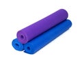 Three rolled yoga exercise mats stacked on white