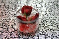 Three rosebuds in vase on pretty patterned tablecloth