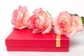 Three roses lie on the red bass box. Gifts on a white background. A gift for the beloved Royalty Free Stock Photo