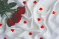 Three roses lie on a white satin fabric