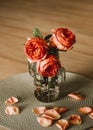 Three roses standing in a glass jar on a wooden floor in daylight Royalty Free Stock Photo