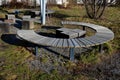 Three round benches in the park. the grill is in the middle of sitting. large wood-paneled crescent moon in a meadow under a pergo Royalty Free Stock Photo