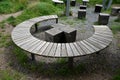 Three round benches in the park. the grill is in the middle of sitting. large wood-paneled crescent moon in a meadow under a pergo Royalty Free Stock Photo