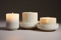 Three round lit soy wax candles in minimalistic white holders against a neutral background, isolated, suggesting