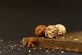 Three round truffle candies and star anise on a wooden board. Dark background with place for text.