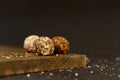 Three round truffle candies on a wooden board. Confectionery crumb.Dark background with place for text.